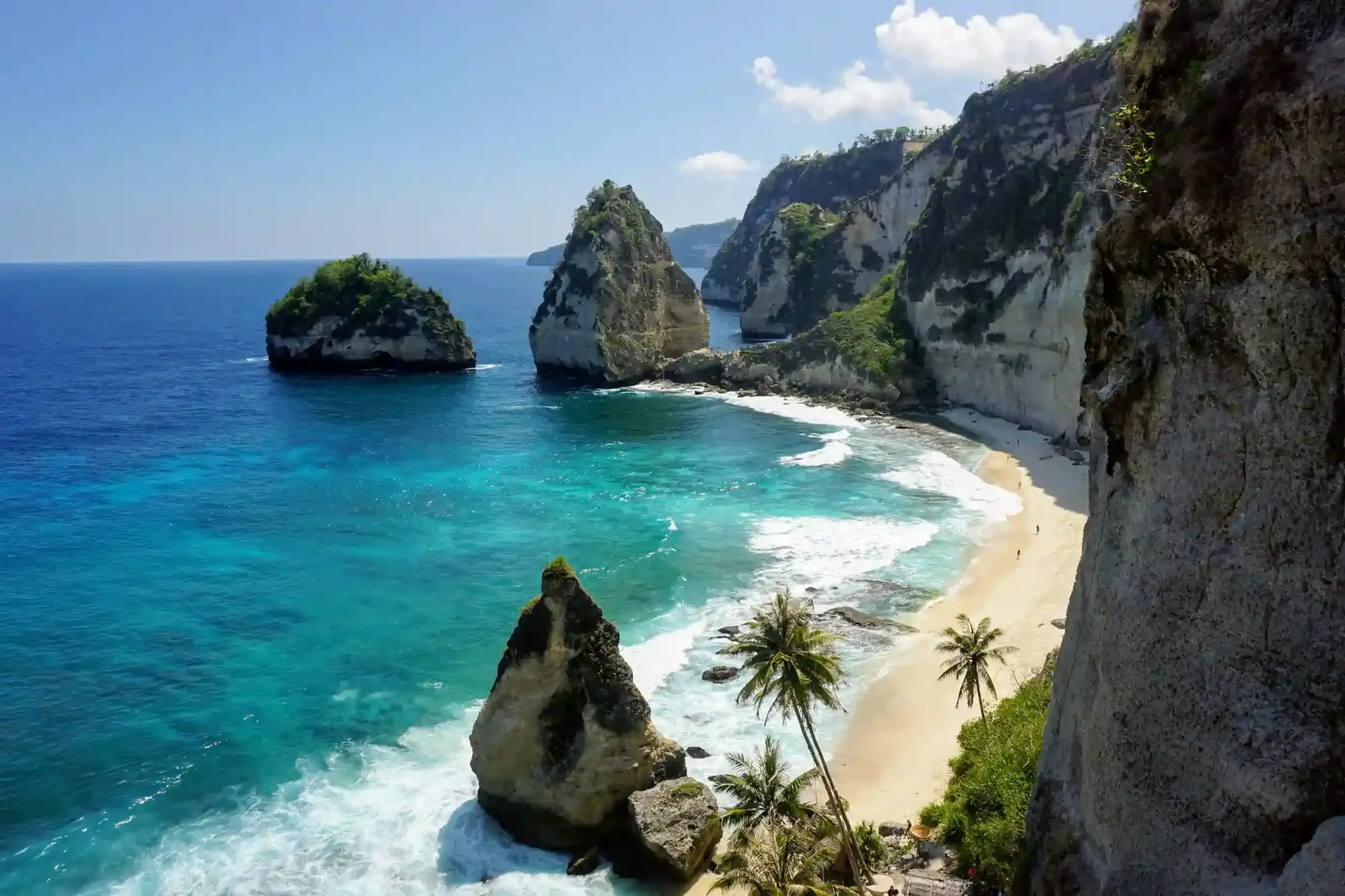 Diamond Beach on Nusa Penida with rock stacks, palms and clear blue water