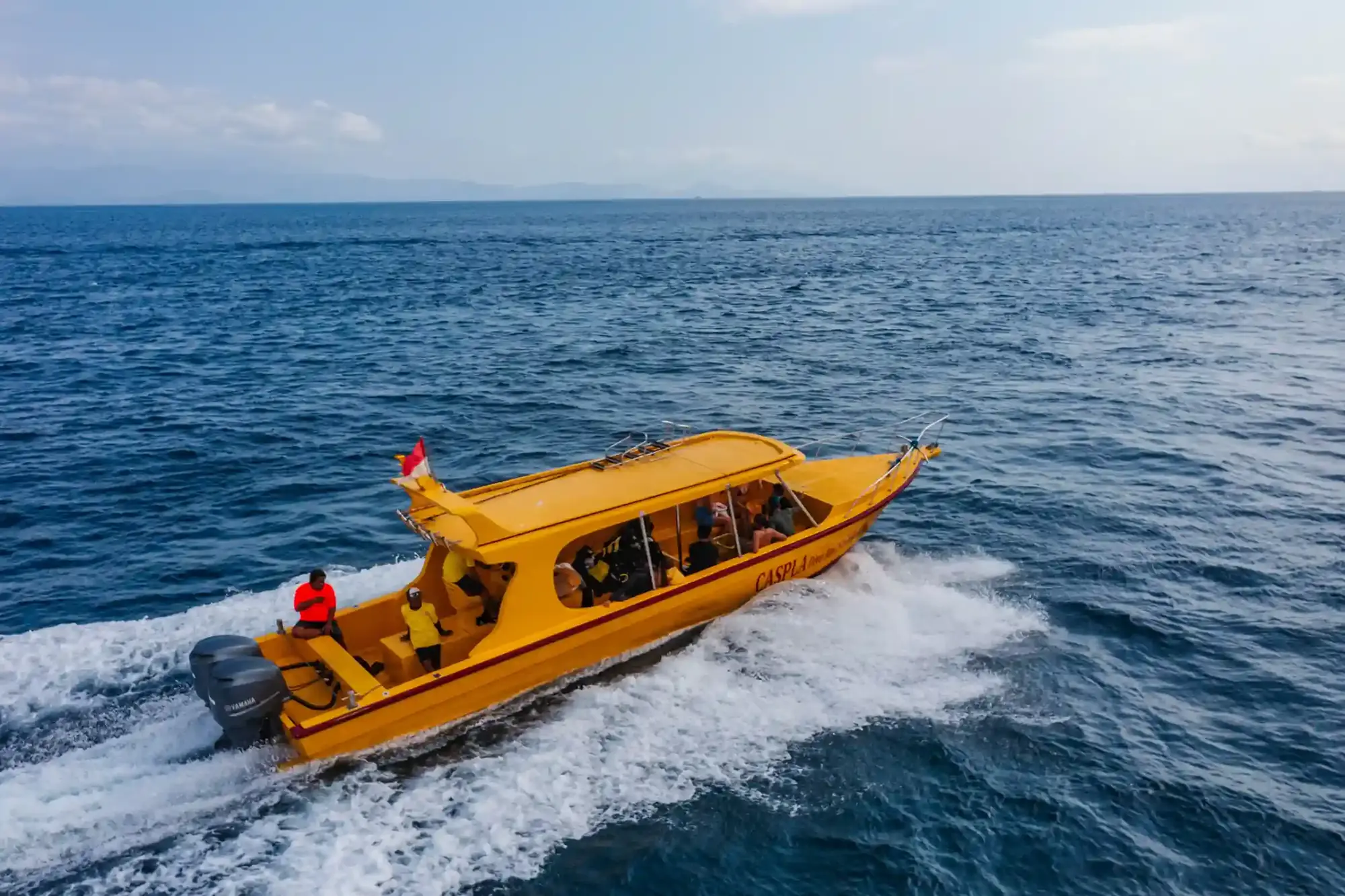 Fast boat crossing open blue water with a wake behind it