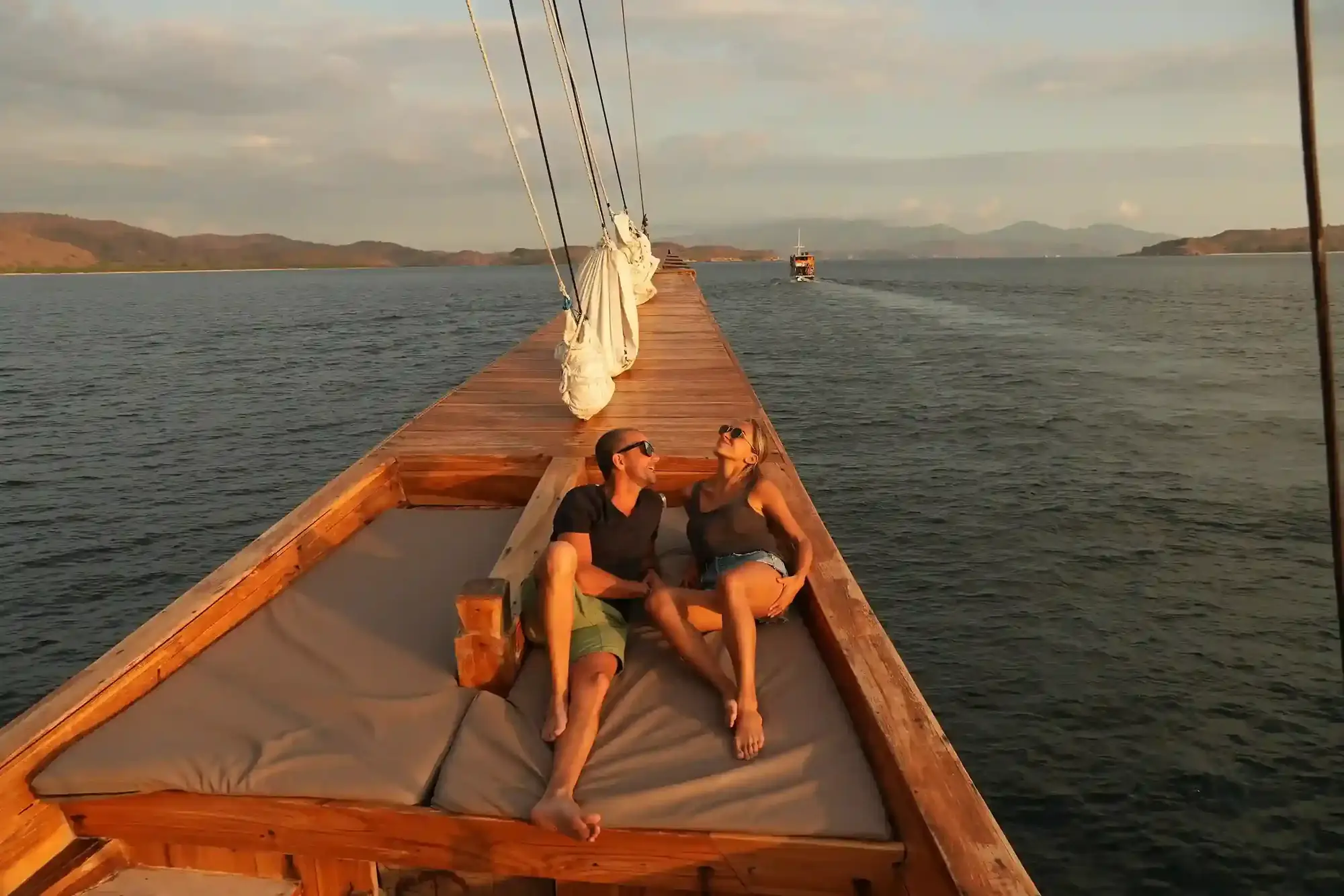 Couple relaxing on the bow of a wooden sailing boat