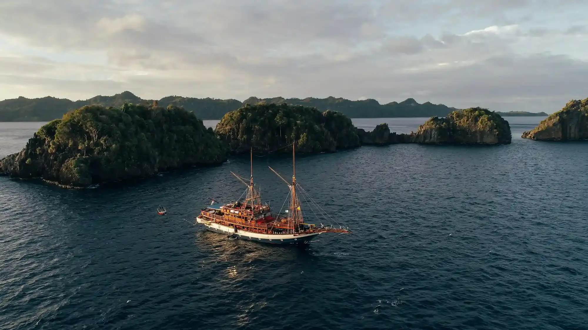 Wooden sailing boat at anchor among green islands